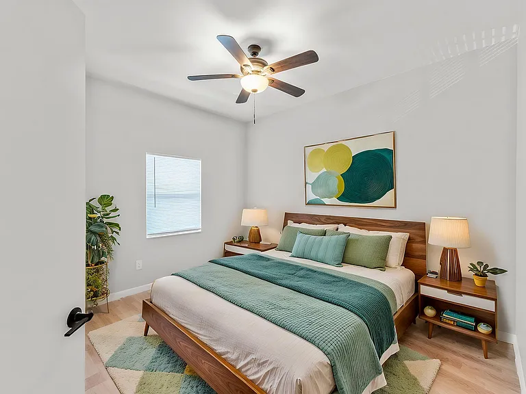 Inviting bedroom with stylish decor, featuring a modern ceiling fan, vibrant artwork, and plush bedding for ultimate comfort.