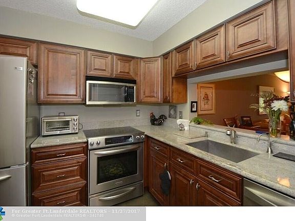 Beautifully updated kitchen with wood cabinets, granite counters & wood tile floor, pass thru window to dining area