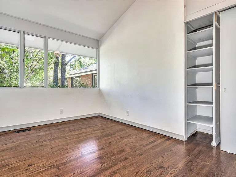 Room featuring a wide window bank, wood-finish flooring, white walls, built-in shelving, and a sloped ceiling