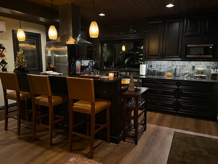 Modern kitchen bar with black granite countertops, pendant lighting and leather bar seating.
