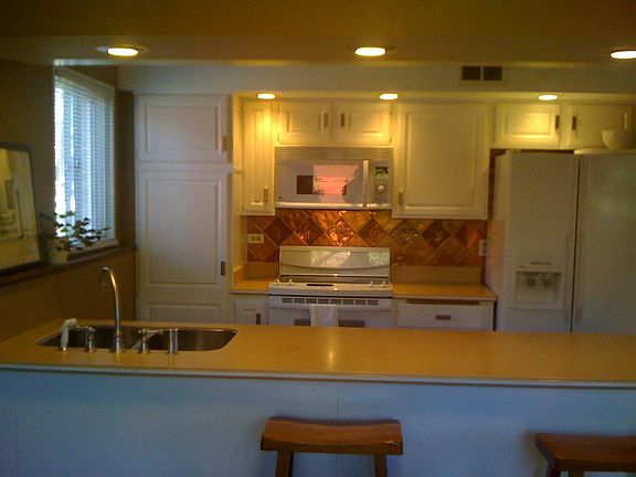 kitchen with eat-in counter adjacent to dining area + den, walk out to patio