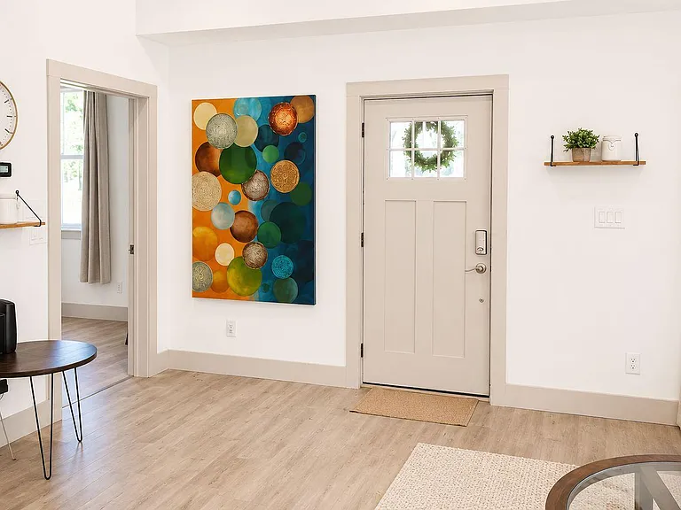 Welcoming entry area with durable wood-style floors, wall shelving, and easy access to adjacent living space and natural ligh