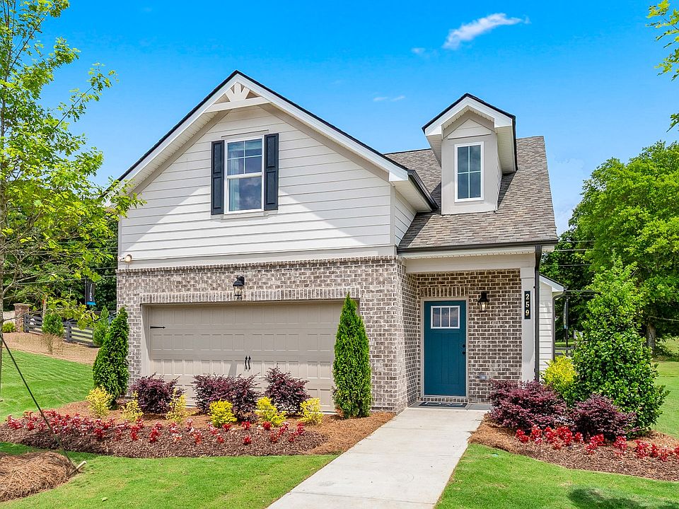 Charming white fiber cement siding and brick accent single family home with teal door by DRB Homes i