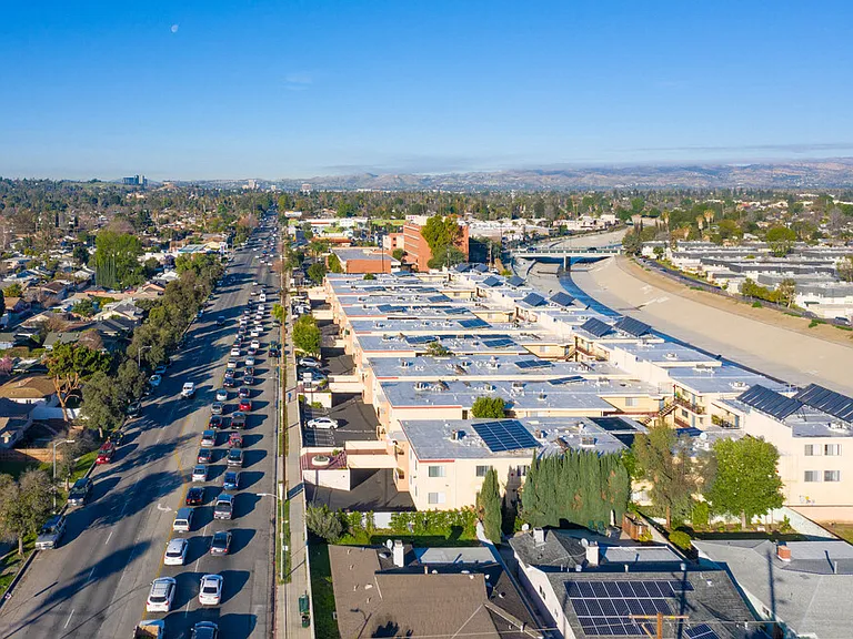 Aerial drone photo of Riverbridge Apartments showing solar panels and energy-efficient white roofs.