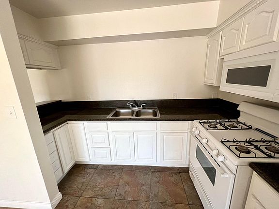 Kitchen with white cabinets, granite countertop, and newly installed microwave & refrigerator!