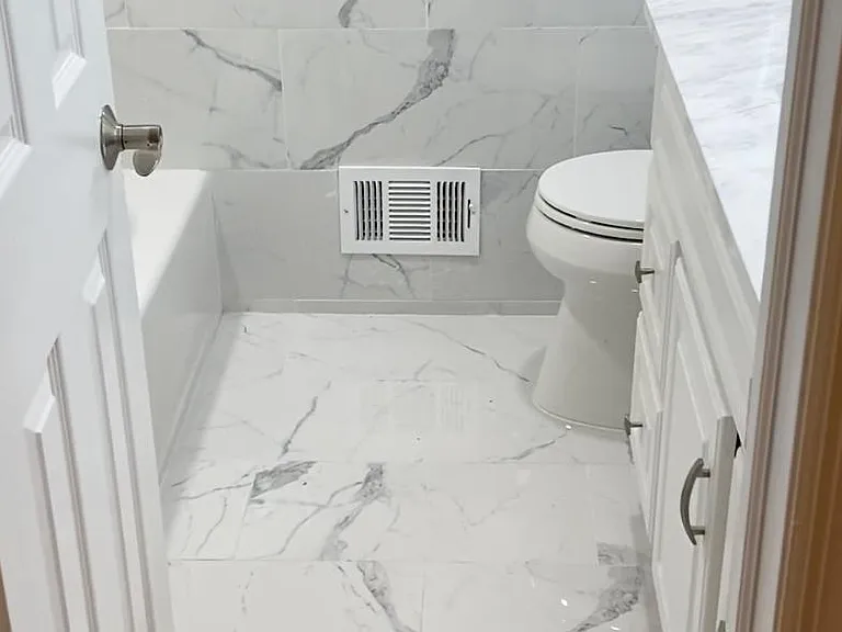 Modern renovated bathroom with marble-style finishes and updated fixtures.
