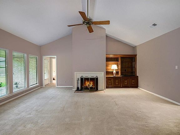 High slanted ceiling with fireplace and built-in looks out on to the patio area.