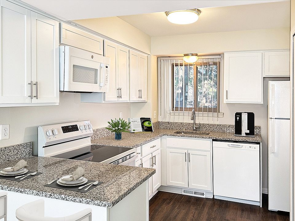 Upscale high end features in newly designed kitchen with wood plank flooring, sleek white cabinetry and granite countertops.