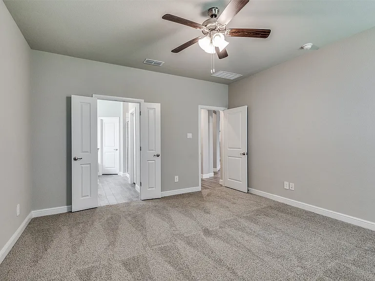 Unfurnished bedroom with light colored carpet and ceiling fan