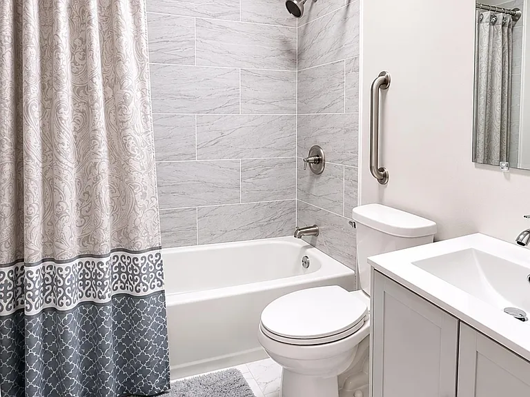 Full bathroom with a tiled tub/shower surround, updated fixtures, and a vanity with storage and mirror.