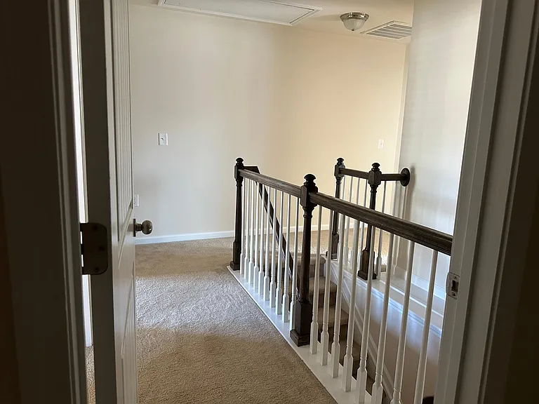 A view from within the laundry room where you can see the top of the stairs. To the immediate left is room 1, to the far left is the main bedroom, to the back right is the second full bathroom , and to the front right is bedroom 2 (three bedrooms upstairs