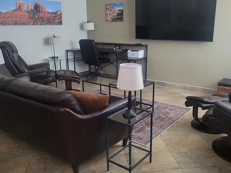 View of living room with 75-in. tv with streaming service, sofa, and 2 very comfortable recliners with separate ottomans.