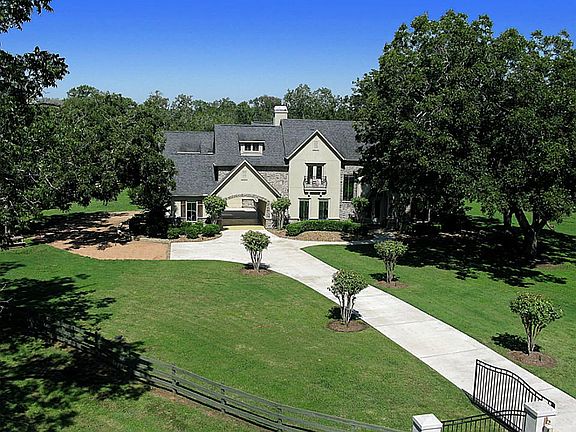 An elegant wrought iron gate set between masculine columns that are complemented by gas lanterns offers the perfect combination of exclusivity and privacy to this remarkable Estate home