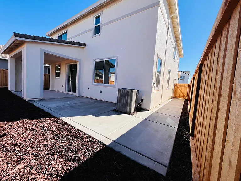 Backyard with extended concrete and low maintenance mulch
