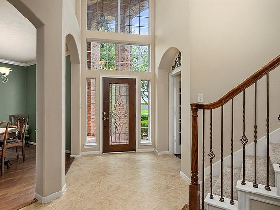 Front foyer with high ceilings and windows that allow for ample natural light throughout downstairs. Formal Dining room on left, Study/Office through doors on right. Staircase leading to second floor in foreground.