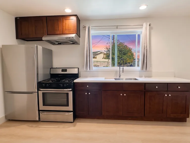 full kitchen with fridge, freezer, range, deep sink, cabinets