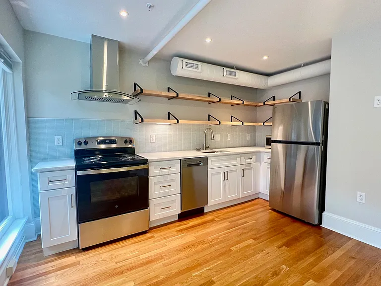 Kitchen "L" wall. Nice expanse of countertop, open maple shelving, good LED lighting.