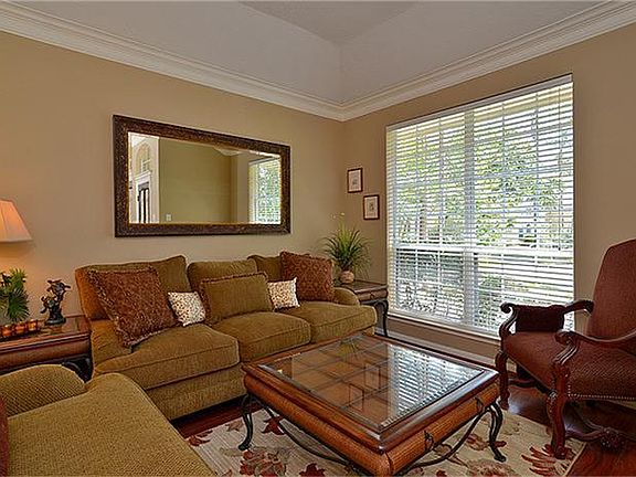 The formal living area has high ceilings, crown molding and neutral paint.