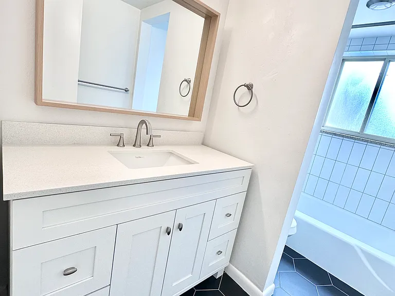 Bright and modern bathroom featuring sleek black hexagonal tiles, a stylish white vanity with ample storage, and a spacious bathtub area. Bright and modern bathroom featuring sleek black hexagonal tiles, a stylish white vanity with ample storage, and a sp