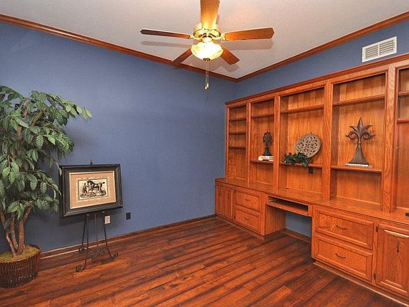 The study is accented with warm wood trim, flooring and wall of shelving and storage.