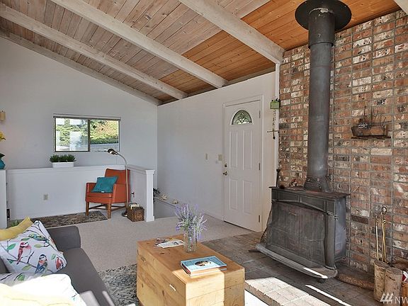 To the left of the wood stove is the main door. The stairs to the lower level are to the left of the front door. This home has been lovingly tended by generations of the same family.  Wall of windows & glass doors is to photographer's back. 