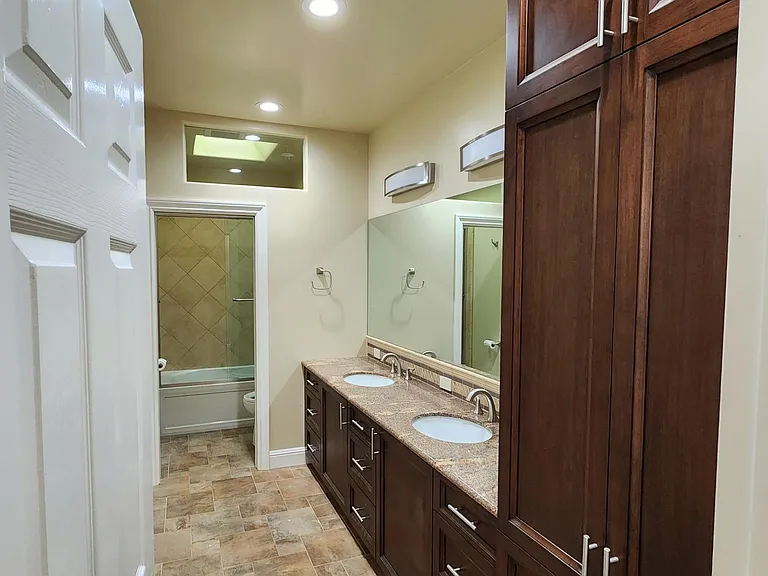 Entry to guest bathroom #1 with custom tile work, ample cabinetry & dual sink vanity.