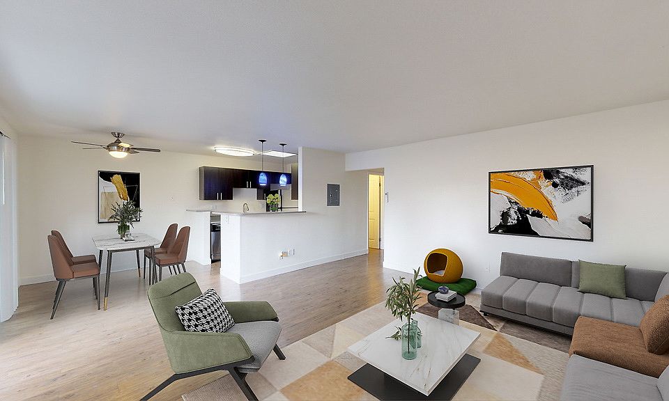 Staged living room and dining area with gally kitchen and hardwood style, vinyl flooring.