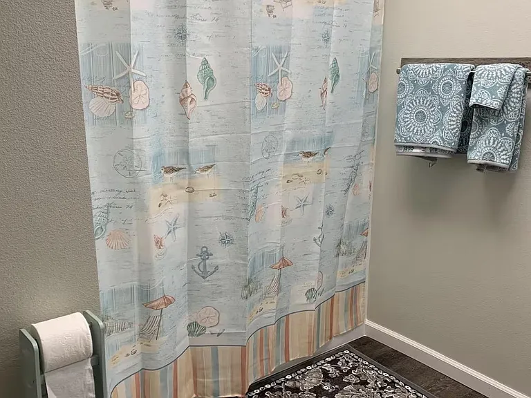 Full bathroom with shower/tub combo, towel storage, and durable flooring for easy everyday upkeep.