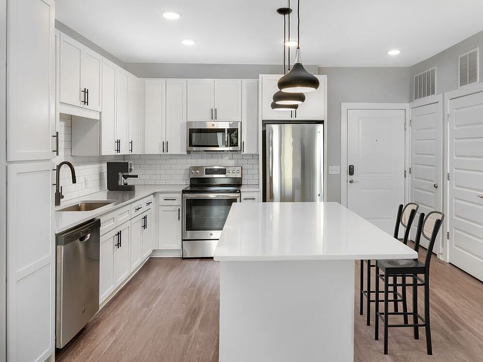 Modern kitchen with white cabinetry, white quartz countertops, and stainless steel appliances