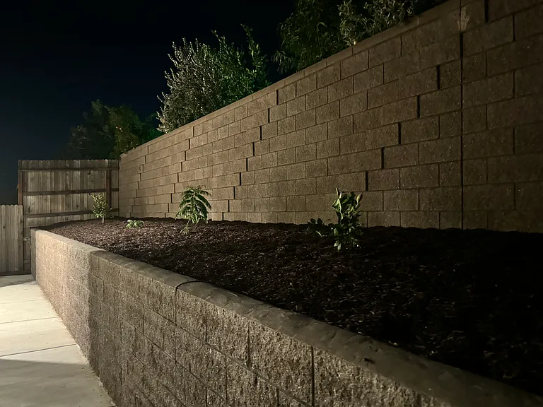 Backyard with retaining wall and plants and weed protection with fabric and bark (mulch)