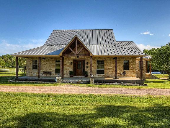 Bask in the warmth of the sun at this limestone custom home w standing seam metal roof & massive wood columns. Wood & iron front door w sidelites. Deep covered front & back porches w wood ceilings &  ceiling fans. - perfect for listening to the birds