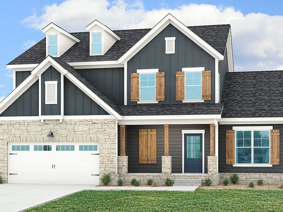 Elegant farmhouse with rustic wood shutters, sleek dark siding, and timeless stone accents in Brush