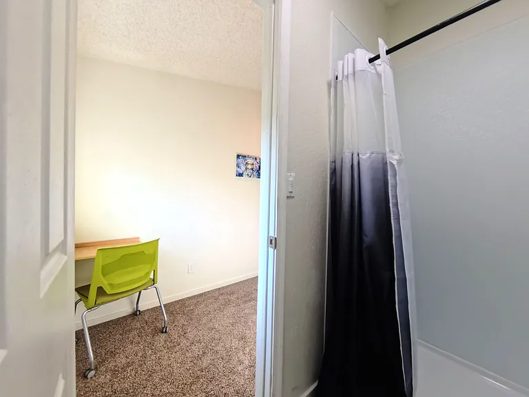 Functional bathroom with a tub/shower combo and curtain, offering convenient access from the adjacent room.