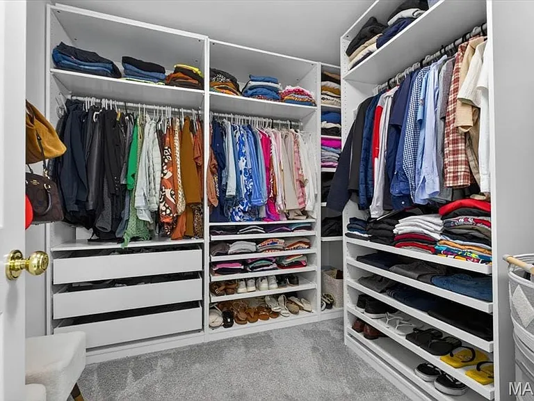 Custom closet system featuring multiple hanging rods, integrated shelving, and pull-out drawers