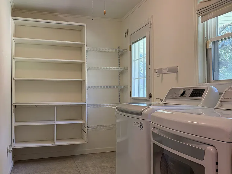 Spacious laundry room featuring abundant built-in storage, utility sink, washer and dryer, and convenient exterior access.