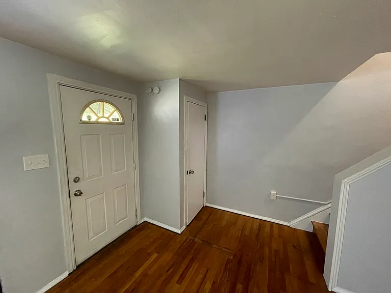 Living room facing main door left, coat closet right in front, stairs to upper level on right