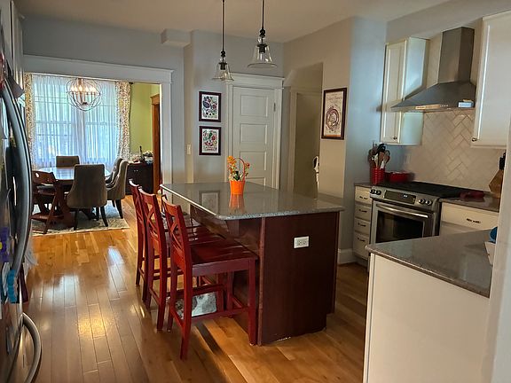 Kitchen with lots of cabinets and large island. Half bathroom door in the background.