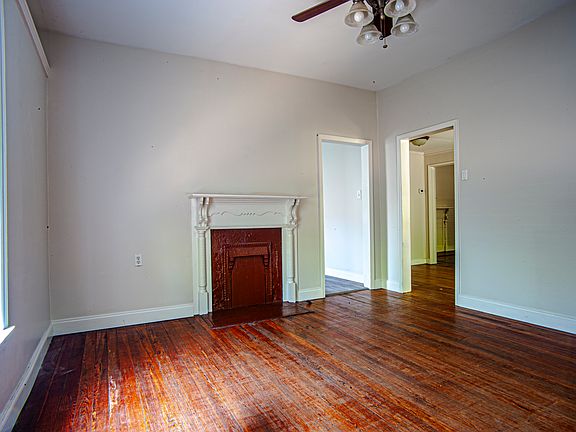 Room one, with view of mantel, kitchen entrance, and entryway.