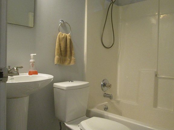 Cheerful tile flooring, pedestal sink, dual flush toilet, tub/shower