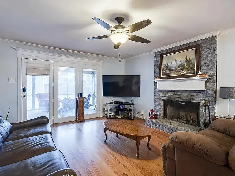 Living area featuring wood-finish flooring and a stone-clad fireplace with a white mantle
