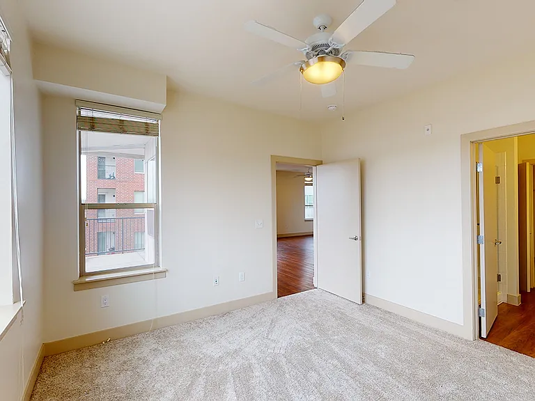 Spacious apartment bedroom with plush carpet flooring.