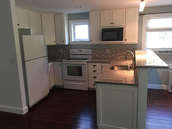 Modern kitchen with granite countertops and dishwasher comes lightly furnished with dishes and cookware.
