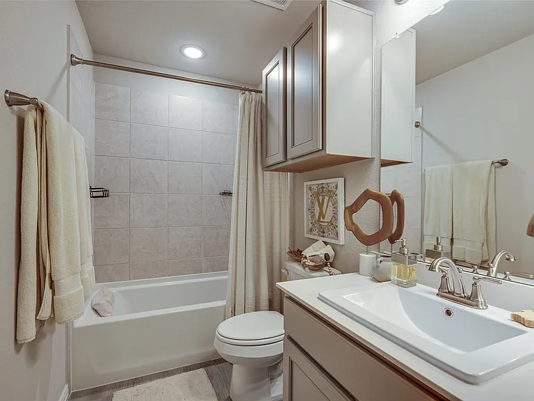 Bathroom featuring a white bathtub, tiled shower surround, recessed lighting, and a vanity with a white countertop and integrated sink