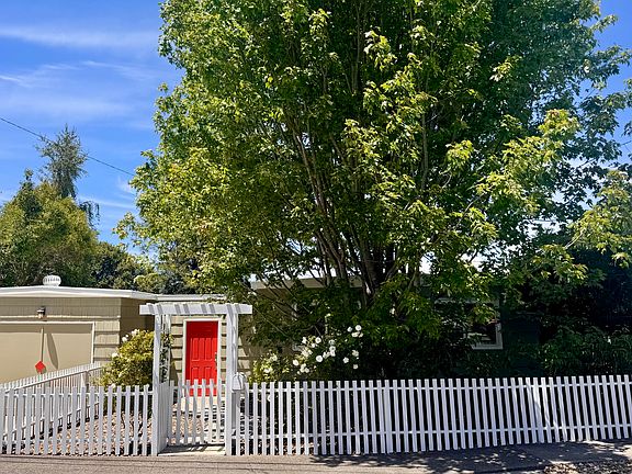 This 1952 bungalow has striking curb appeal with mature trees, private fenced frontage, and a welcoming architectural entry anchored by a striking red front door.