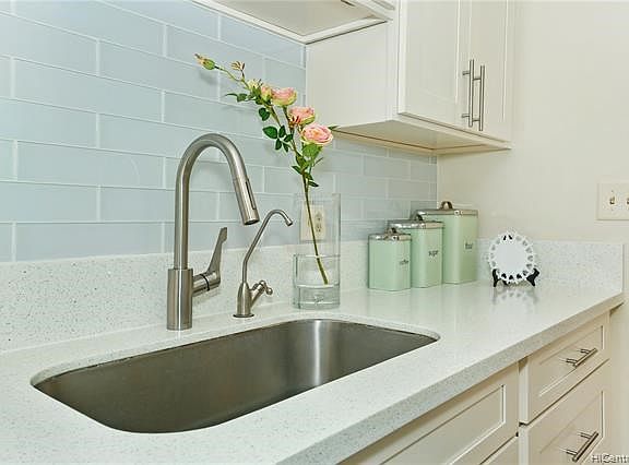 The soft white glass subway tile nicely complements the white quartz countertops.  Deep single bin sink with disposal will be great for cleaning up those bigger pans.  All gleaming and spic and span clean!