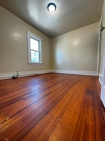 Bright and comfortable bedroom with a window overlooking the driveway, offering good natural light throughout the day. Features hardwood flooring and a convenient walk-in closet. Clean, well-maintained space ideal for restful and practical living.