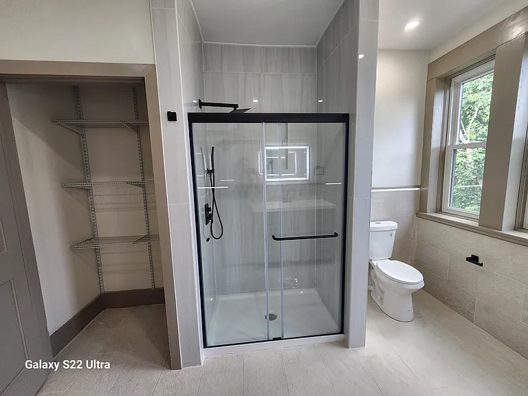 Linen Closet with Plenty of Storage Space. Tiled Shower with a Glass Door and Two Showerheads.