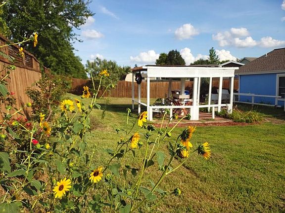 Back yard with a two tables and enough seating for 9 people.