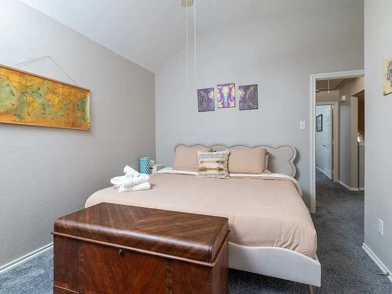Bedroom 3 features soft neutral bedding, wall art, a TV, room-darkening curtains and a cozy atmosphere. Ideal for resting after a long day, with towels provided for your stay.