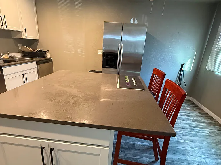 Eat-in kitchen with a large island, ample cabinet storage, and stainless-steel refrigeratorideal for meals and prep.